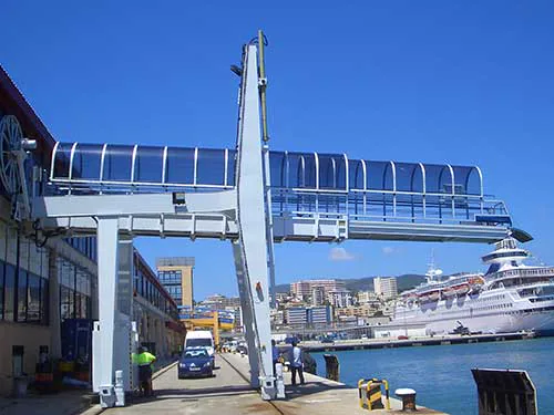 Pasarela de embarque acristalada en una terminal portuaria, con un crucero atracado
