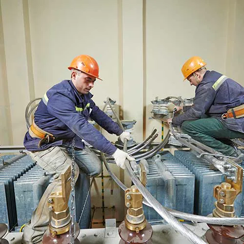 Dos operarios trabajando sobre un transformador eléctrico