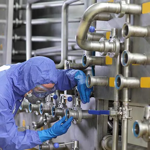 Técnico manipulando tuberías de acero inoxidable en una sala limpia