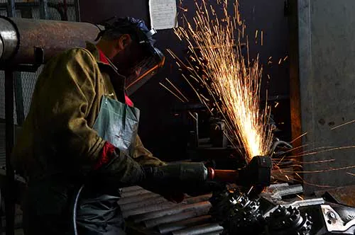 Operario desbarbando una pieza metálica en el taller